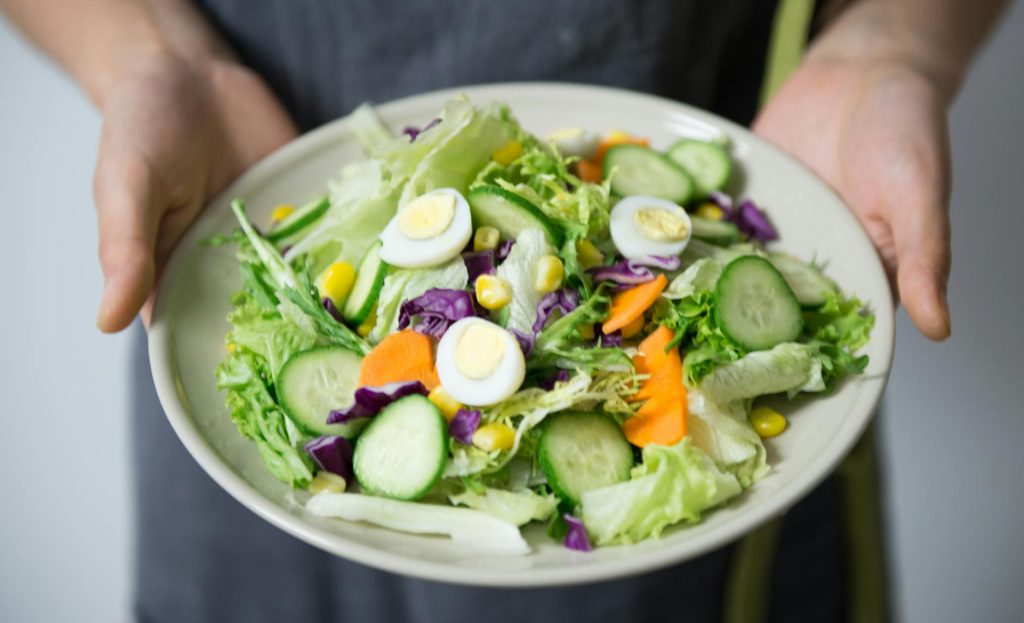 person holding plate of cobb salad